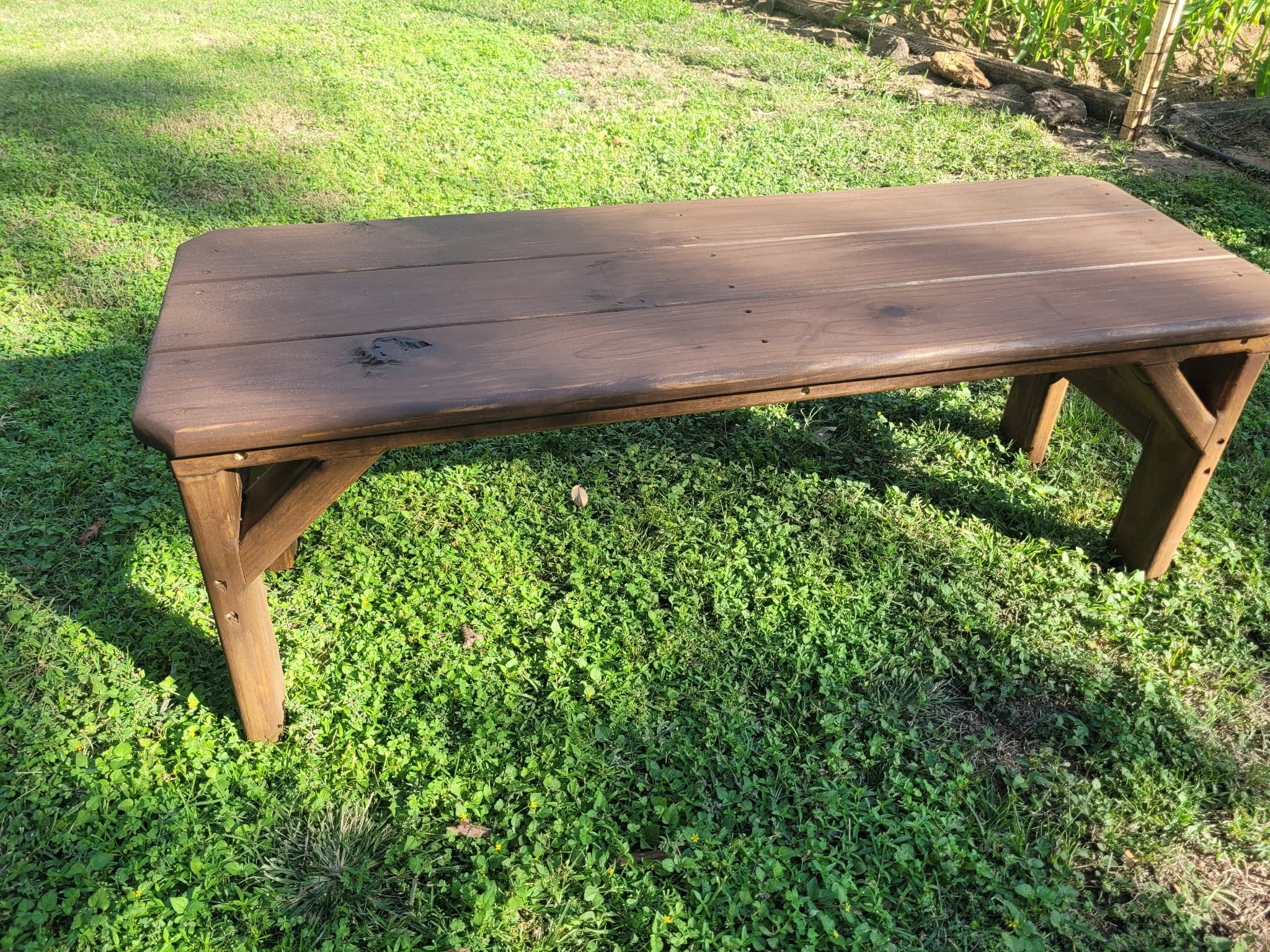 Simple stained-pine garden bench with cross-braced legs.